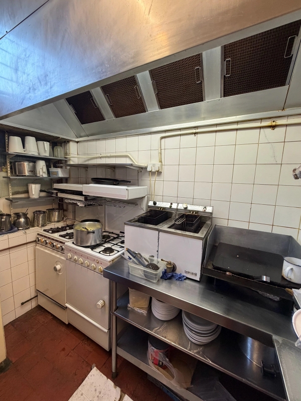 Commercial cafe kitchen location featuring stainless steel deep fryers, gas stove cooktops, and white tiled backsplash, Love Locations SE27.