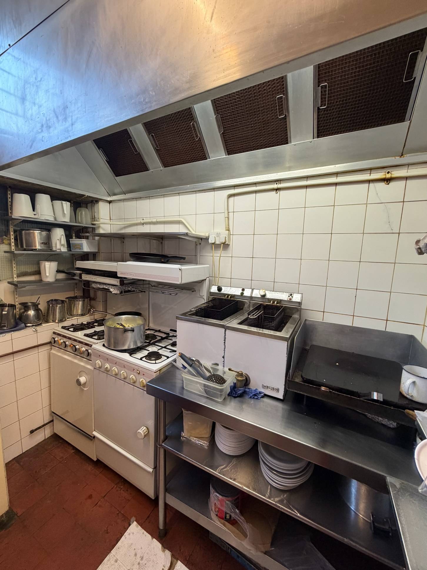 Commercial cafe kitchen location featuring stainless steel deep fryers, gas stove cooktops, and white tiled backsplash, Love Locations SE27.