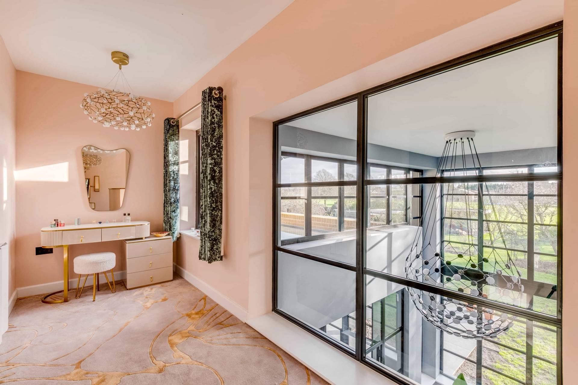 Pastel pink room showing an internal crittall glass window overlooking the double-height entrance hall, Love Locations CB2.
