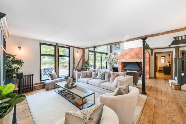 Grand double-height living room inside an Essex luxury barn conversion featuring an authentic open brick fireplace, Love Locations.