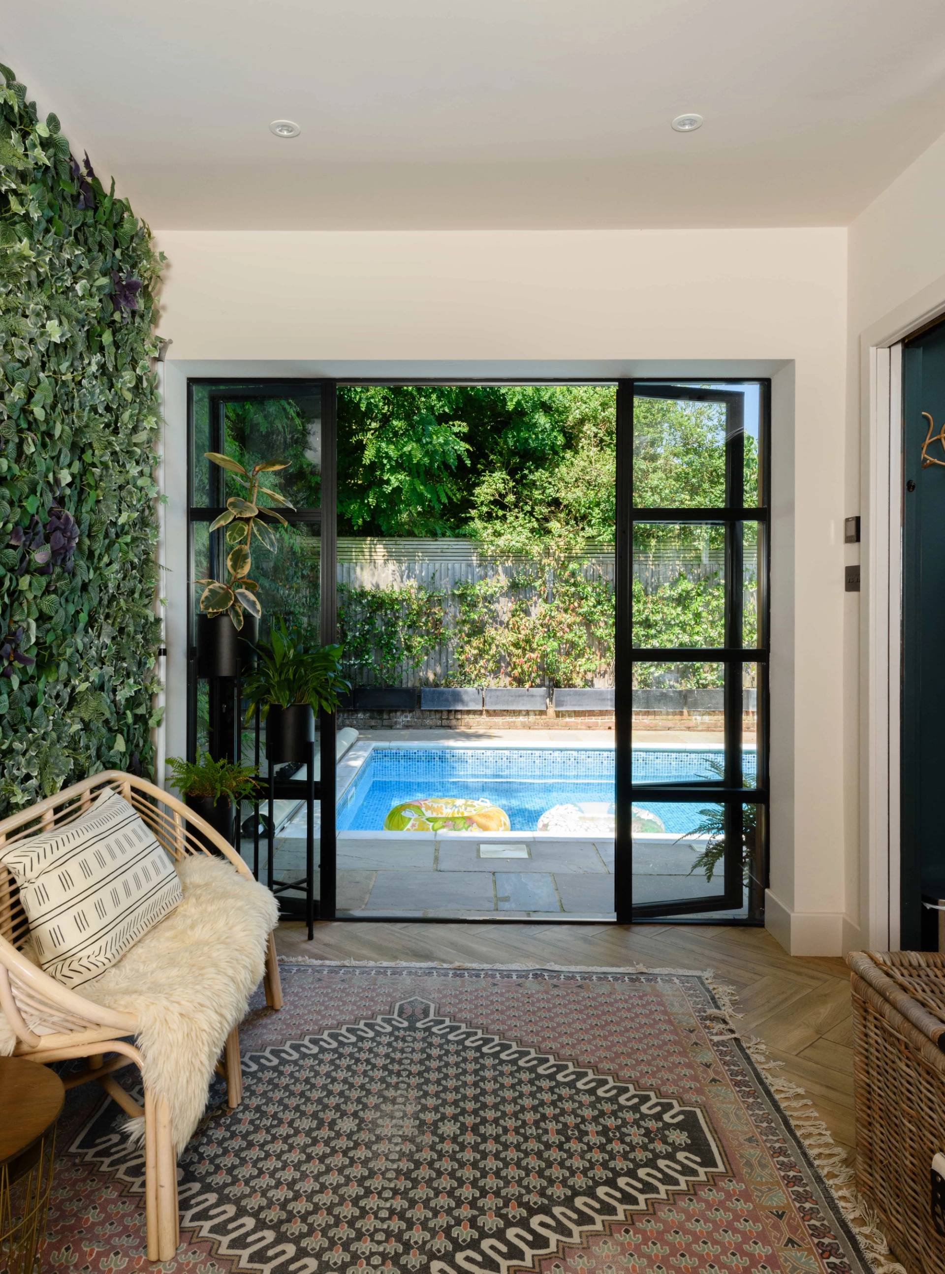Open glass doors looking out from a pool house onto an outdoor swimming pool, Love Locations TW11.