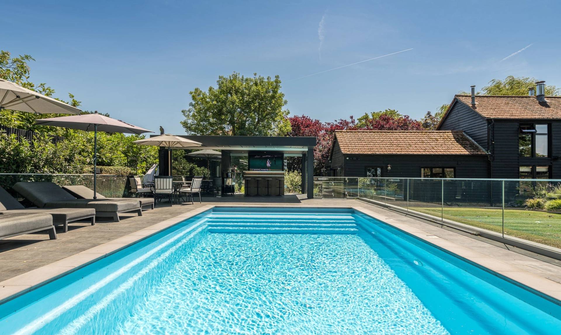Premium residential pool location house featuring a black weatherboarded barn backdrop and pristine sun terraces, Love Locations.