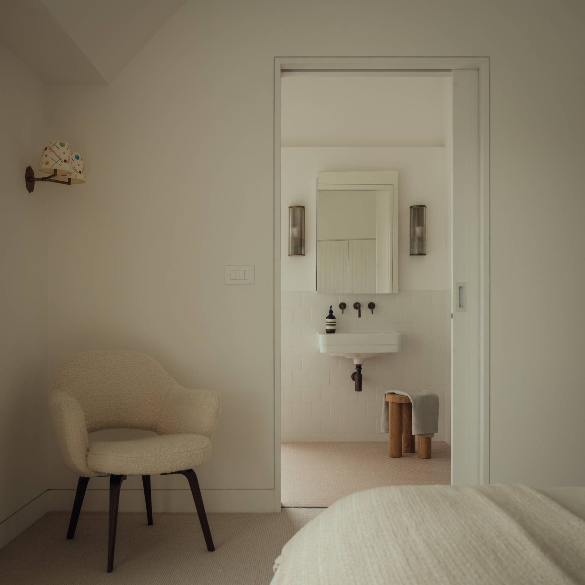 Spacious guest suite showing a plush boucle armchair and an open doorway into an ensuite bathroom, ideal for luxury interior features, Love Locations SO20.