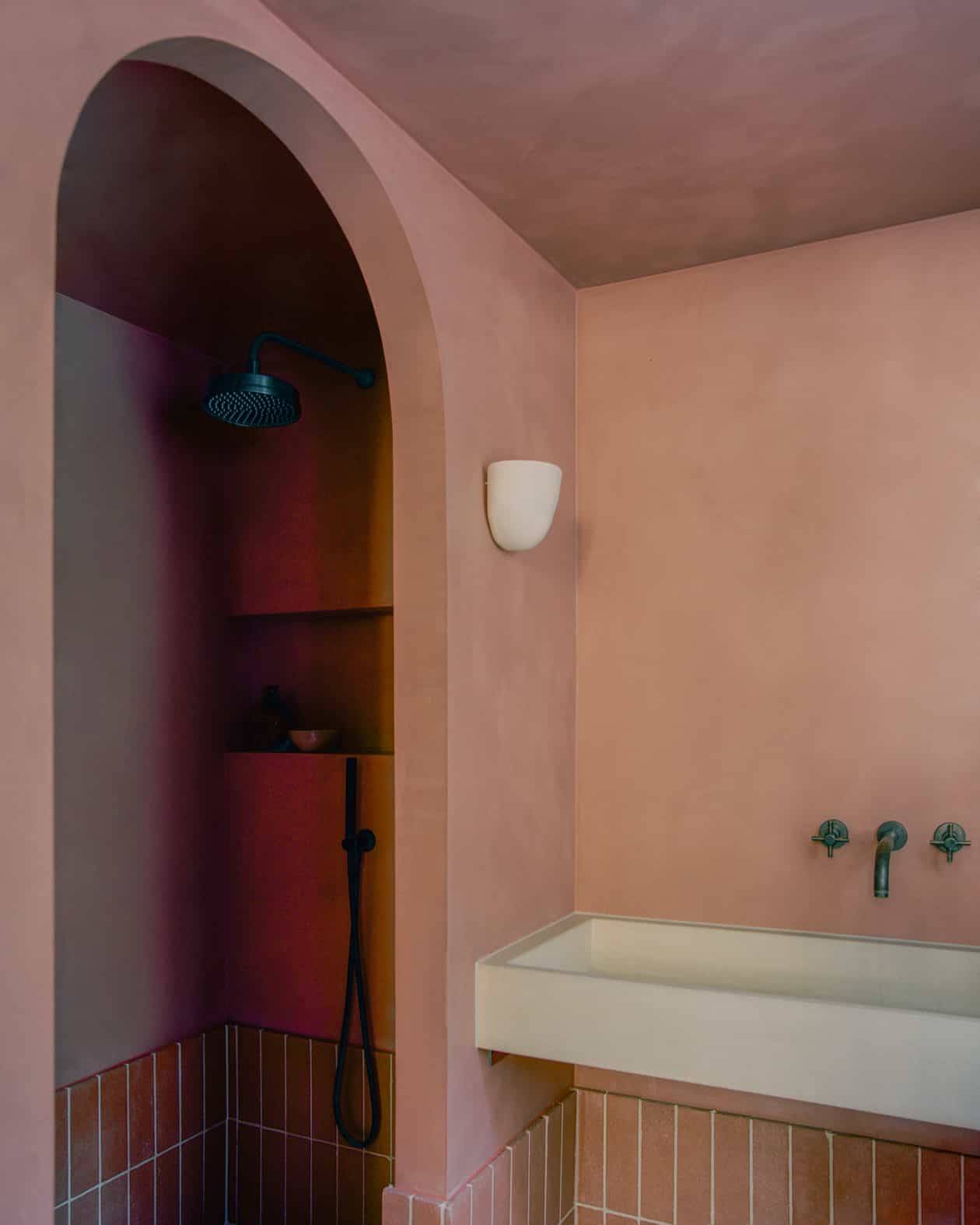 Dusky pink clay plaster bathroom featuring an arched shower nook and white stone washbasin, ideal for beauty editorials, Love Locations SW4.