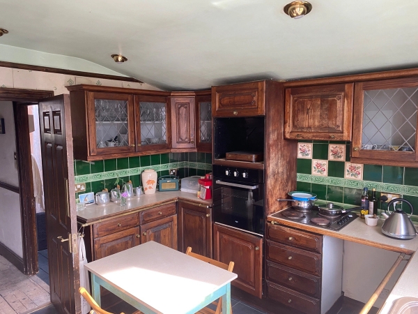 Compact L-shaped kitchen layout showcasing rich timber cupboards, an integrated stovetop, and an open layout, perfect for gritty home commercials, Love Locations SE25.