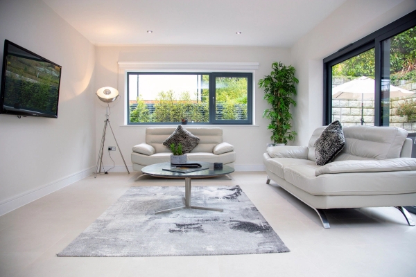Bright contemporary lounge location house featuring white leather sofas and large anthracite window frames, perfect for drama filming, Love Locations.
