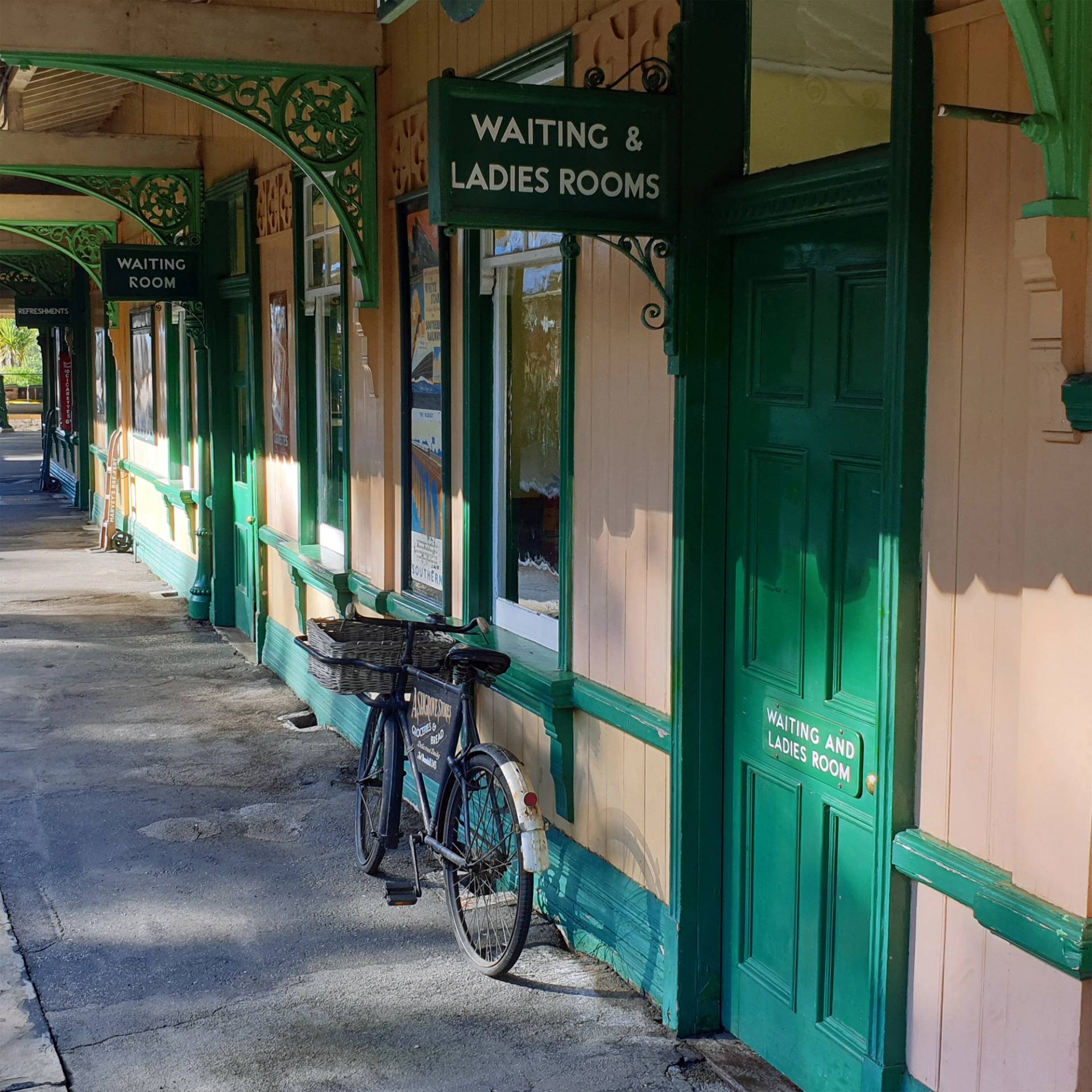 Station platform walkway showing green waiting room doors and a vintage bicycle, perfect for period film establishing shots, Love Locations.