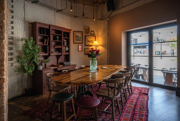 Private dining room or tasting suite featuring a long wooden banquette table, vintage Persian rug, and a large display bookcase, the ultimate backdrop for high-end interview content via Love Locations SW16.