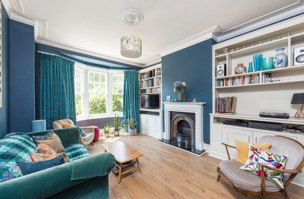 Period living room location house showing a traditional fireplace mantelpiece and custom white built-in bookshelves, Love Locations.