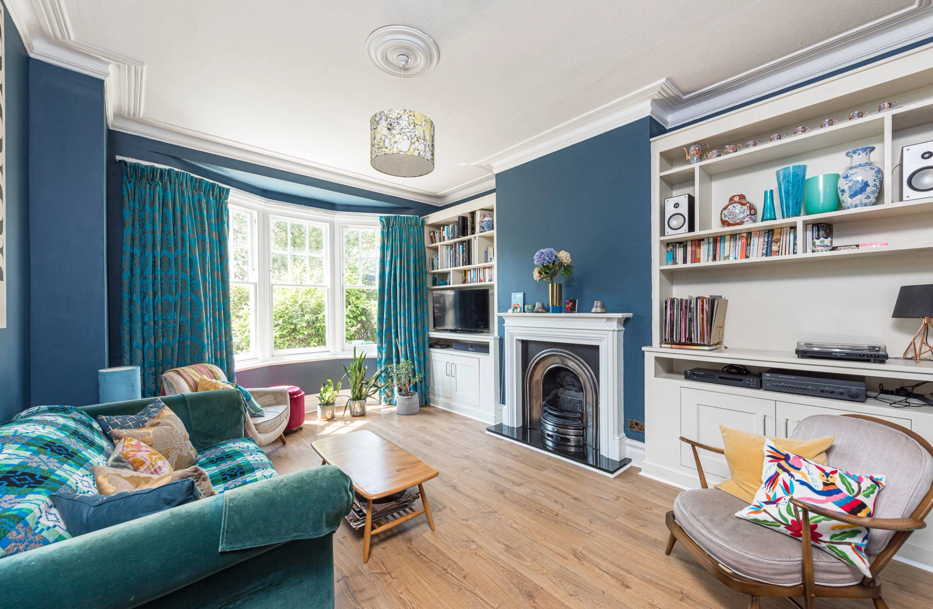 Period living room location house showing a traditional fireplace mantelpiece and custom white built-in bookshelves, Love Locations.