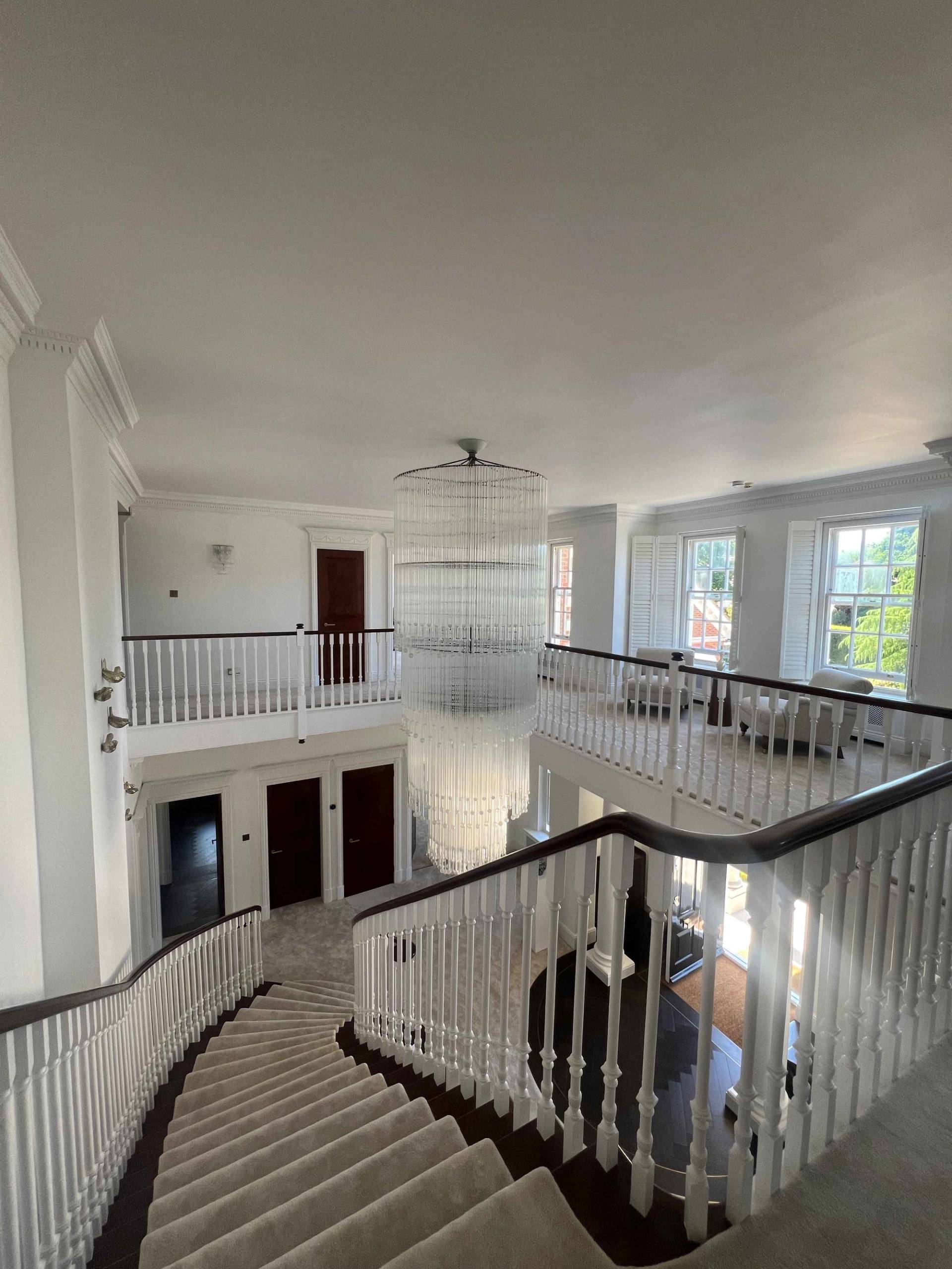 Galleried landing looking down onto a double-height entrance foyer with grand piano and crystal chandelier, Love Locations BR7.