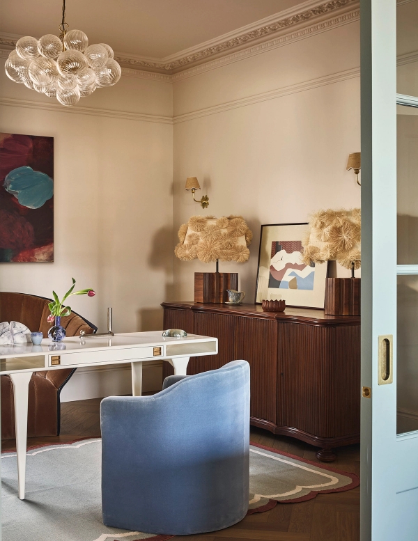 Formal dining room view showing a white dining table, blue armchair, and vintage sideboard cabinet, Love Locations SE21.
