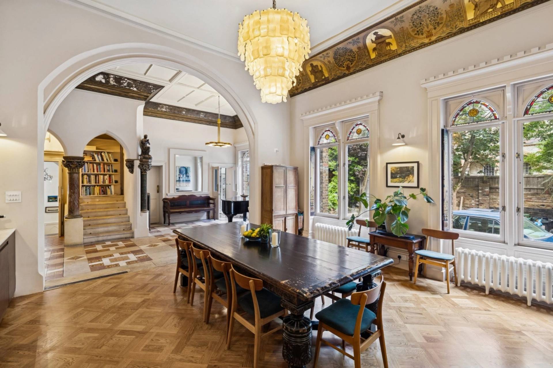 Broad perspective of the formal dining hall filming venue in Hampstead London NW3 by Love Locations, featuring gothic arched windows, wooden flooring, and a crystal chandelier.