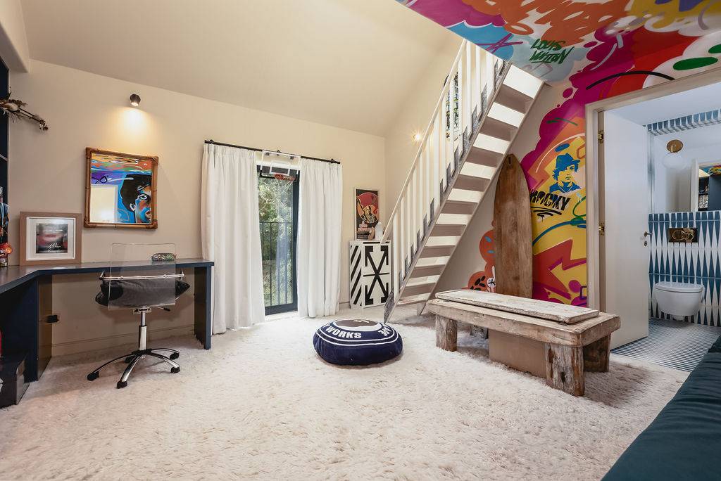 Home office space and bedroom featuring a colorful urban graffiti mural wall and wooden bench seating, Love Locations GU32.