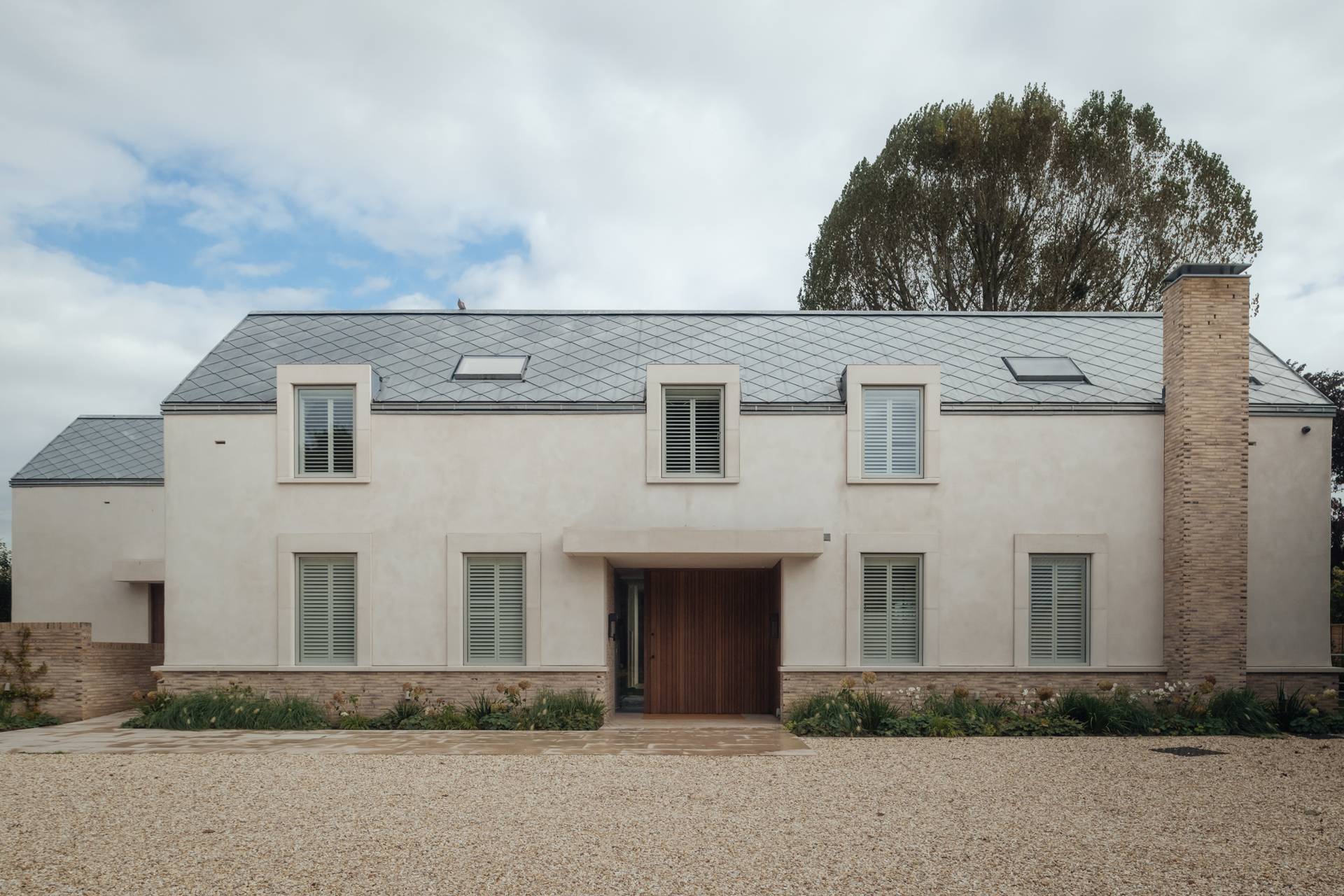 Front exterior facade establishing shot of a modern Stockbridge country home with gravel driveway and lime-wash plaster walls, perfect for TV drama filming via Love Locations.