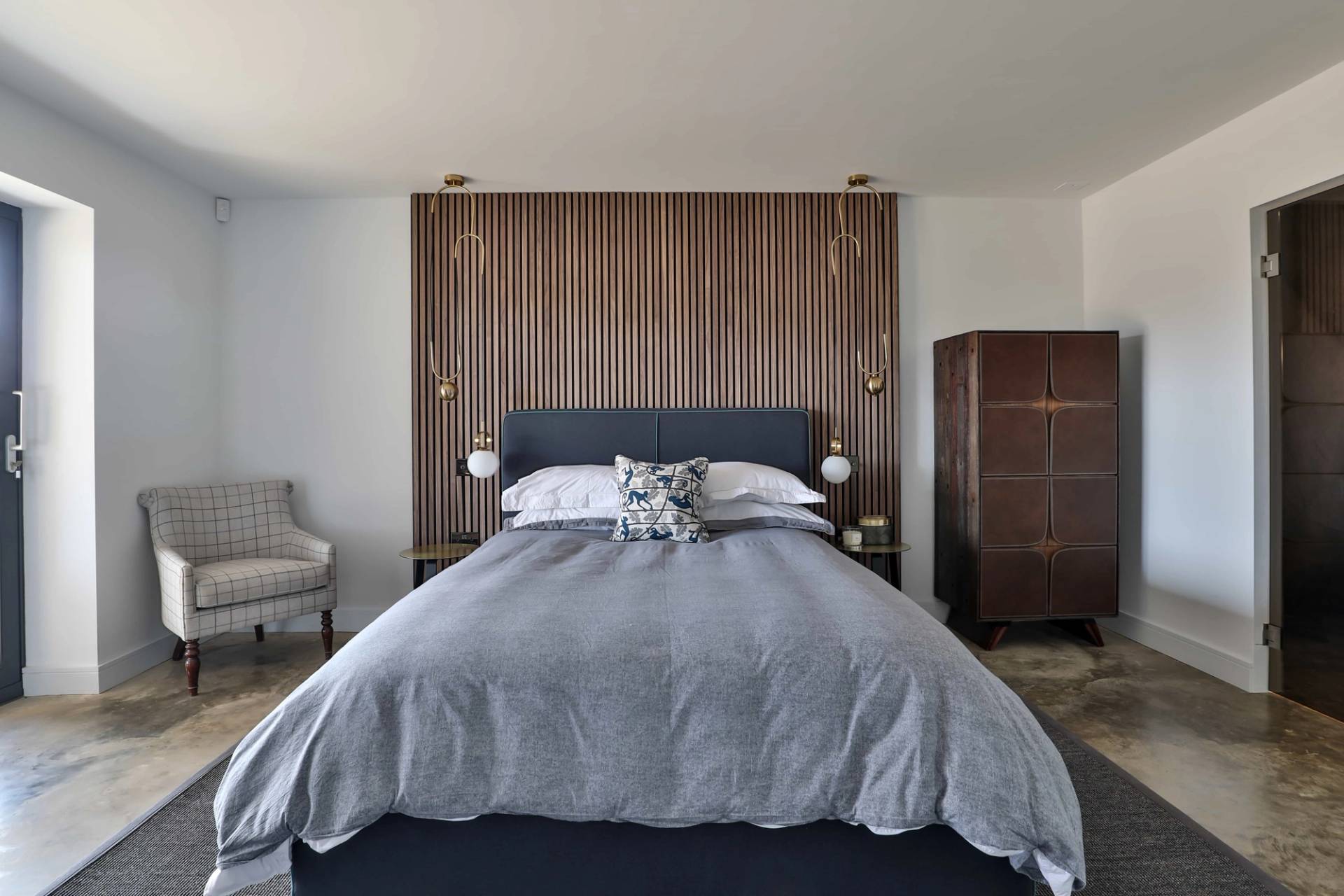 Master bedroom suite featuring a navy velvet bed frame set against a slatted wood wall panel, Love Locations CV23.