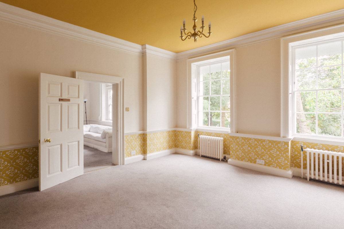Yellow-accented reception room view looking through white panelled doors into an adjoining bedroom, Love Locations.
