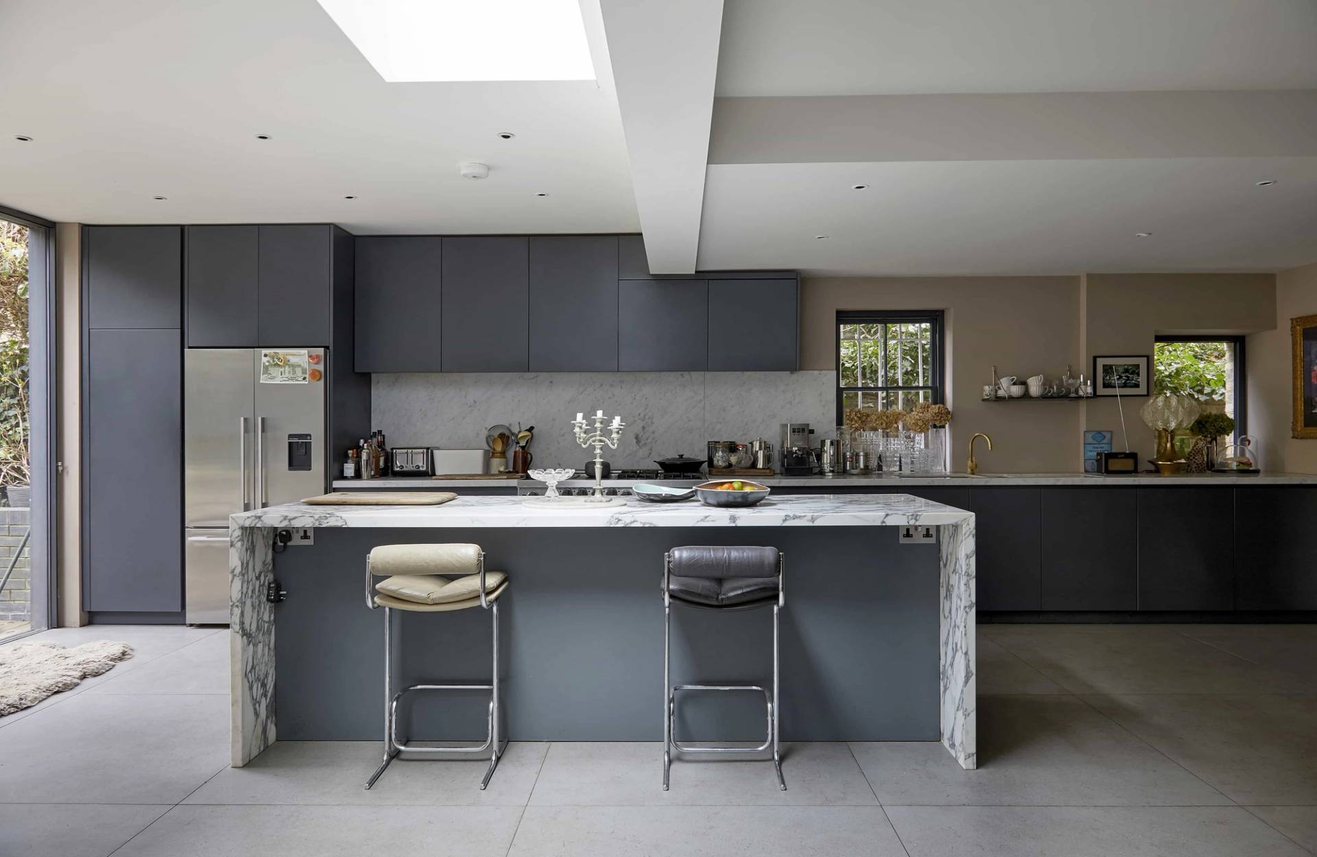 Symmetrical shot of a dark veined marble kitchen island with stainless steel taps and dark grey cabinetry, Love Locations N16.