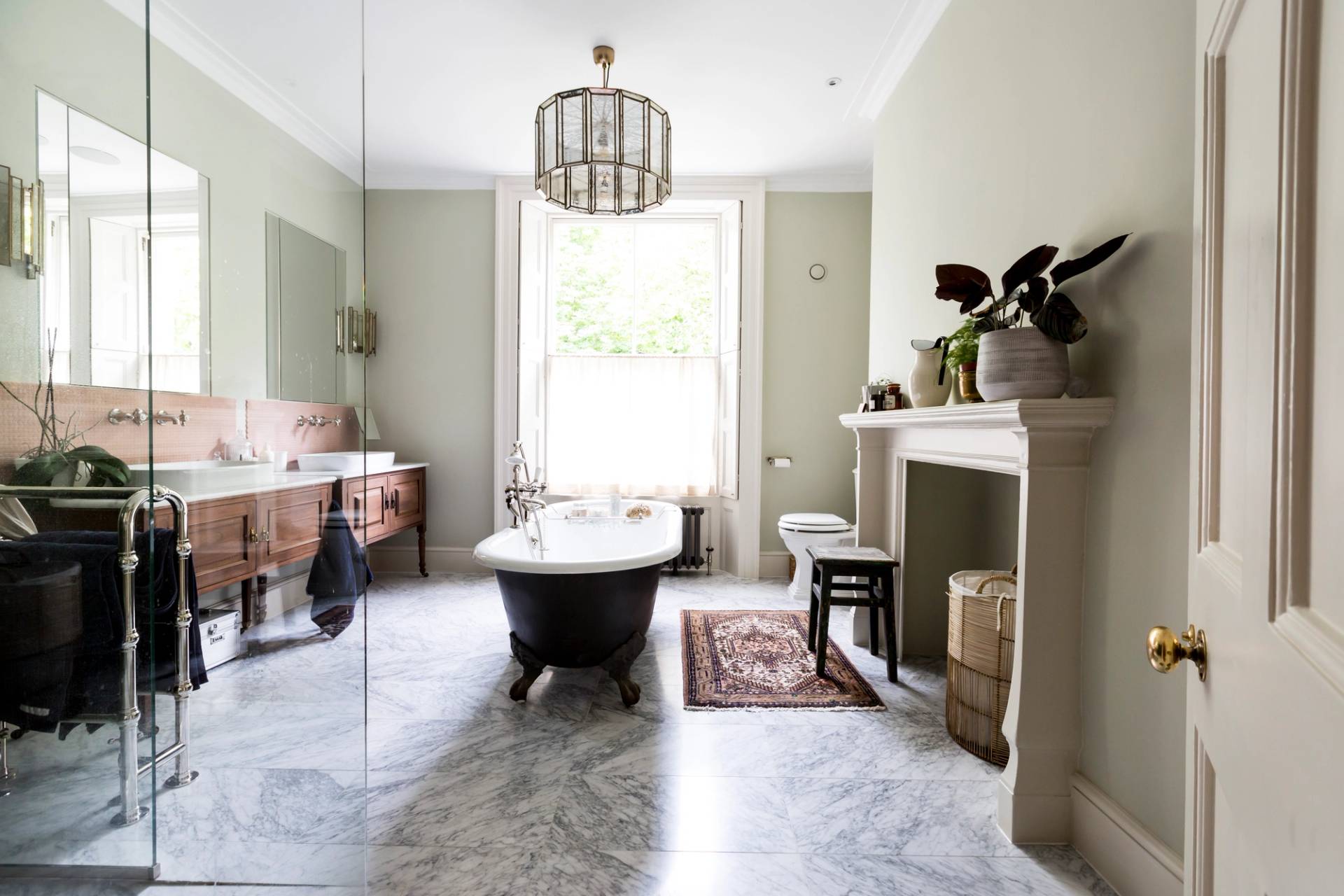 Spacious sage green master bathroom location in Camberwell, SE5 with marble tiled floor and black clawfoot bathtub via Love Locations.