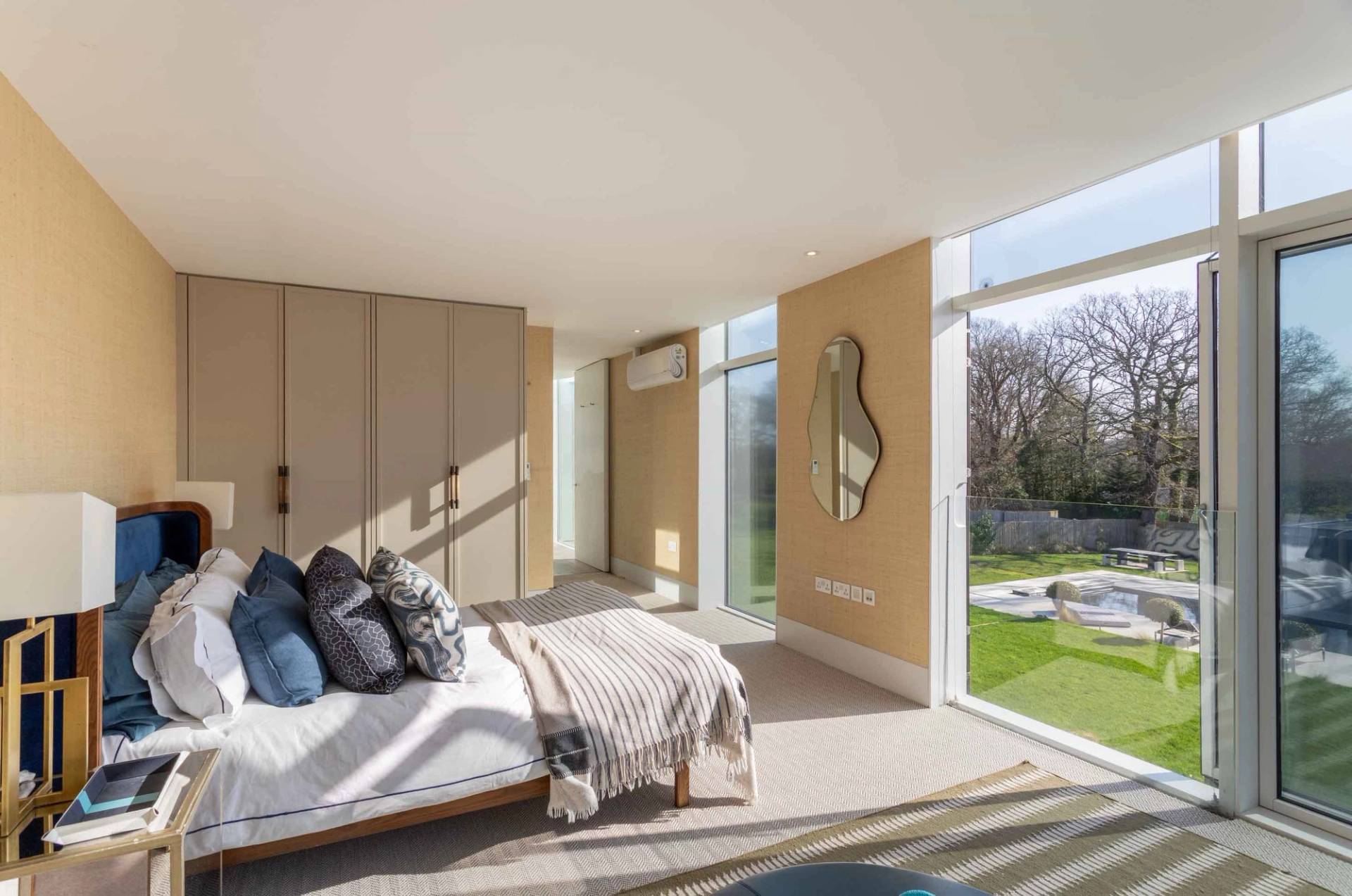 Love Locations airy bedroom location Godalming Surrey GU8: Light-flooded bedroom featuring a statement full-length wavy mirror and concrete-finish walls, perfect for fashion lookbook shoots.