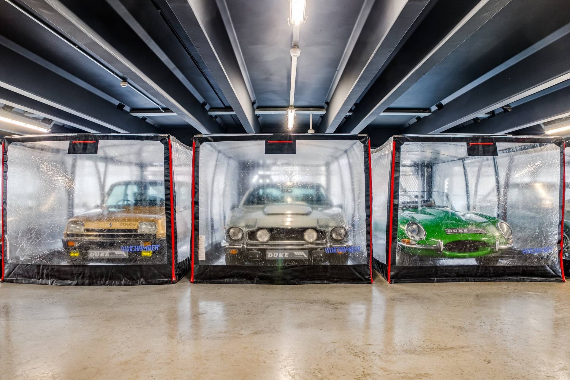 Row of classic cars in inflatable protective storage units in a West London car showroom by Love Locations.