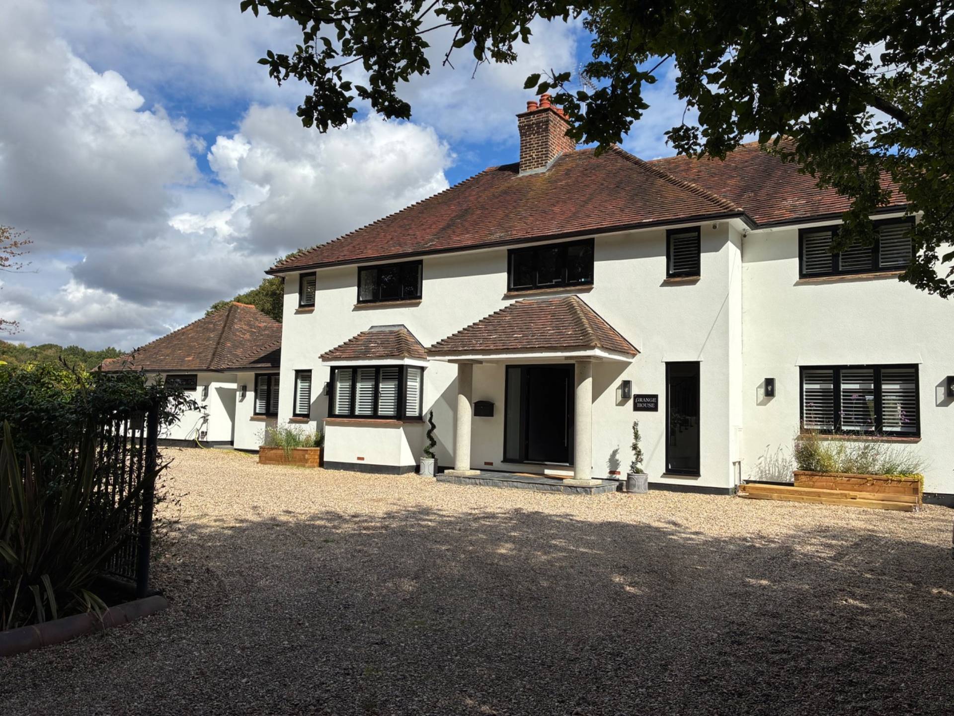Front entrance driveway and facade view of a stunning white location home in Essex CM4 available through Love Locations, with a gravel drive and dark roof tiles.