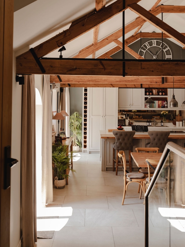 Sunlit hallway passage leading from a modern shaker kitchen into an expansive barn reception area, perfect for interior design catalog features, Love Locations.
