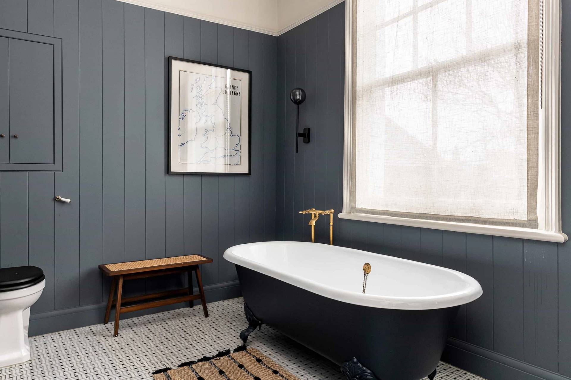 Spacious master bathroom with dark grey wall panelling, black roll-top clawfoot bathtub, and sash windows, ideal for luxury wellness and skincare campaigns, Love Locations NW6.
