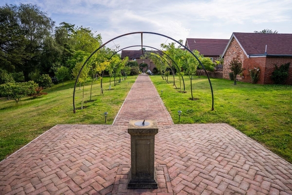 Elegant brick garden pathway with iron arches leading through the estate grounds, a romantic Sussex wedding venue by Love Locations.