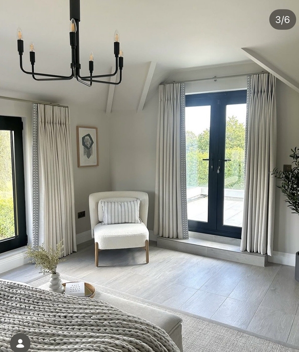 Airy neutral bedroom location property in Essex CM4 via Love Locations, with full-length windows, soft grey curtains, a white accent armchair, and light wood flooring.