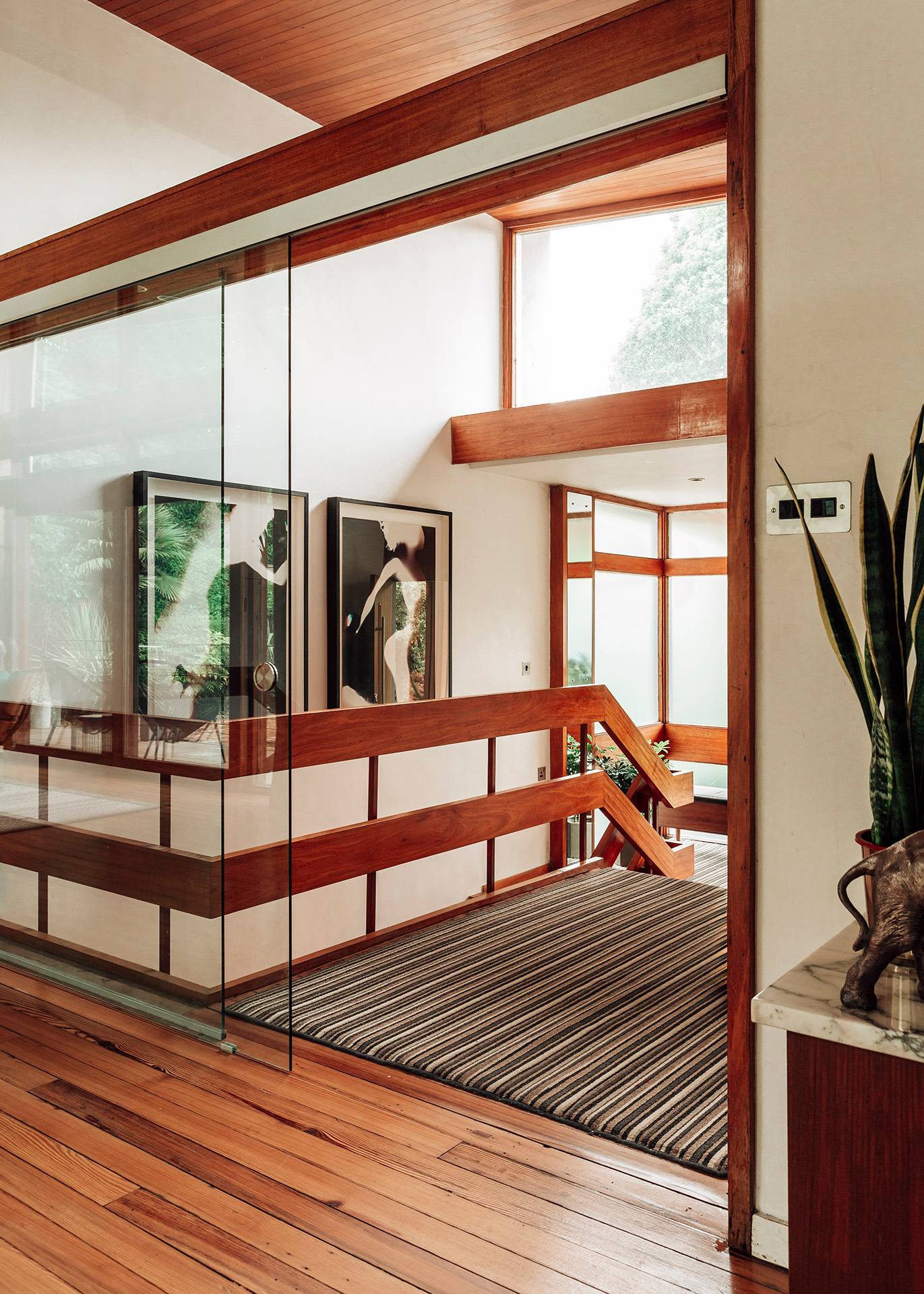 Mid-century wooden staircase landing framed by large abstract artwork and glass partitions in Bromley, BR1, Love Locations.