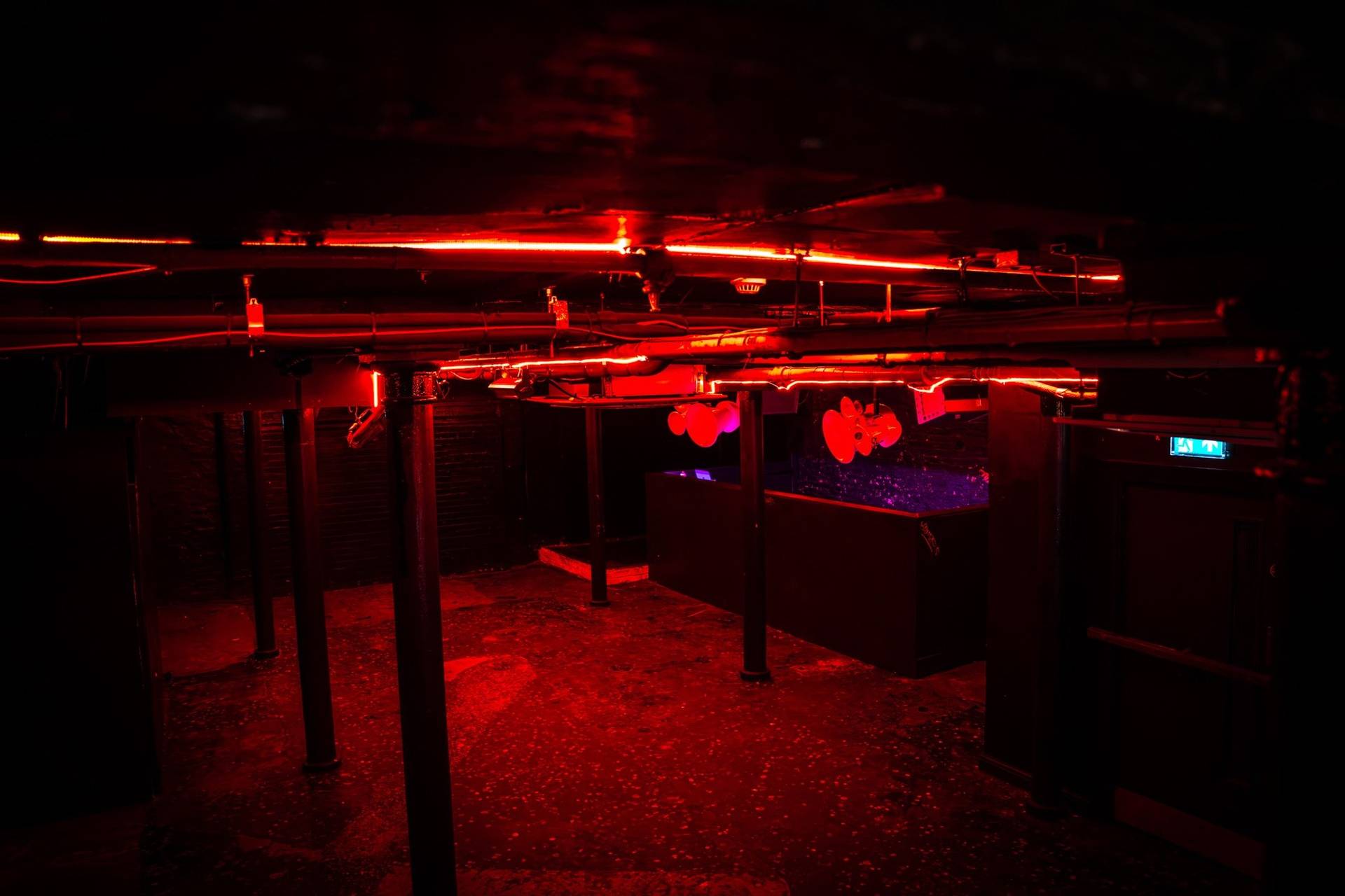 Dark club room shoot location under vivid red LED light bars in a Cheetham Hill venue from Love Locations.