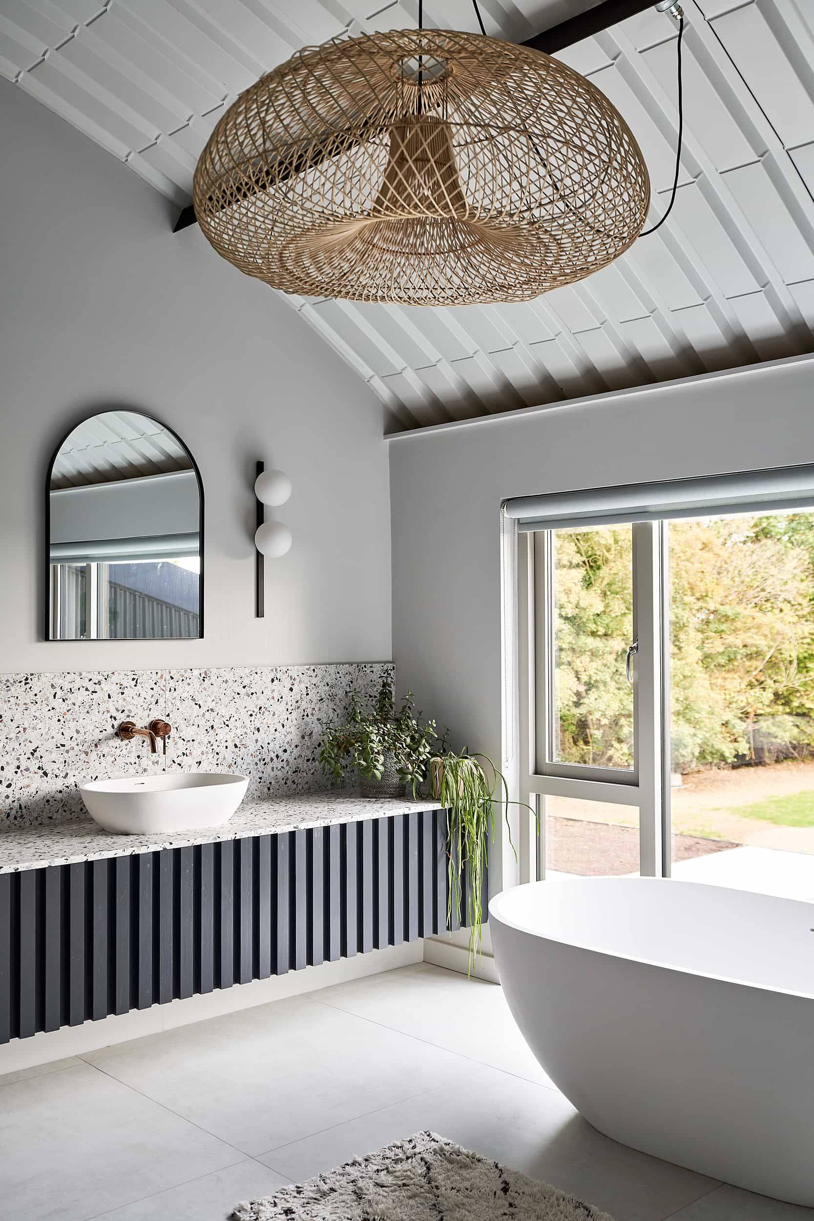Luxury bathroom with a freestanding white bathtub set against vertical white wall tiles and dark panelling, Love Locations IP30.