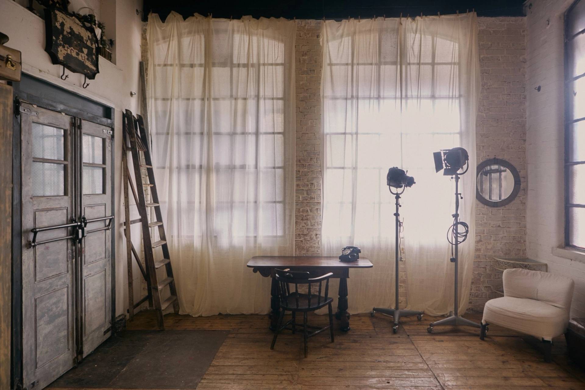 Daylight industrial photo studio location featuring large Crittall windows draped with white sheer curtains and authentic wooden floorboards, Love Locations EN5.