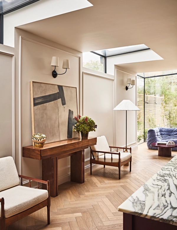 Sunlit hallway landing featuring a dark wood console table, skylight roof, and floor-to-ceiling glass doors, Love Locations SE21.