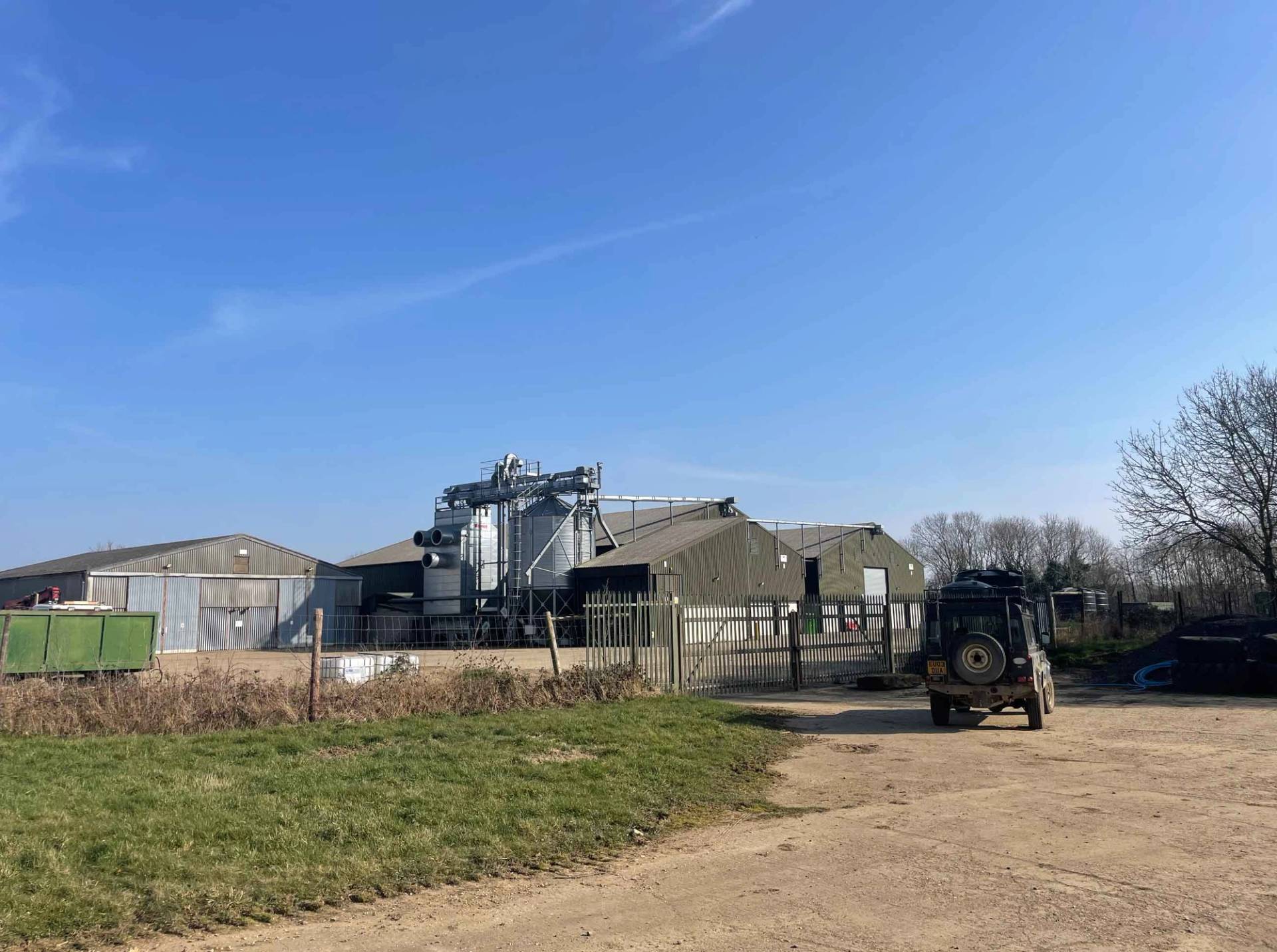 Farmyard complex showing traditional agricultural buildings, silos, and open concrete yards, Love Locations.