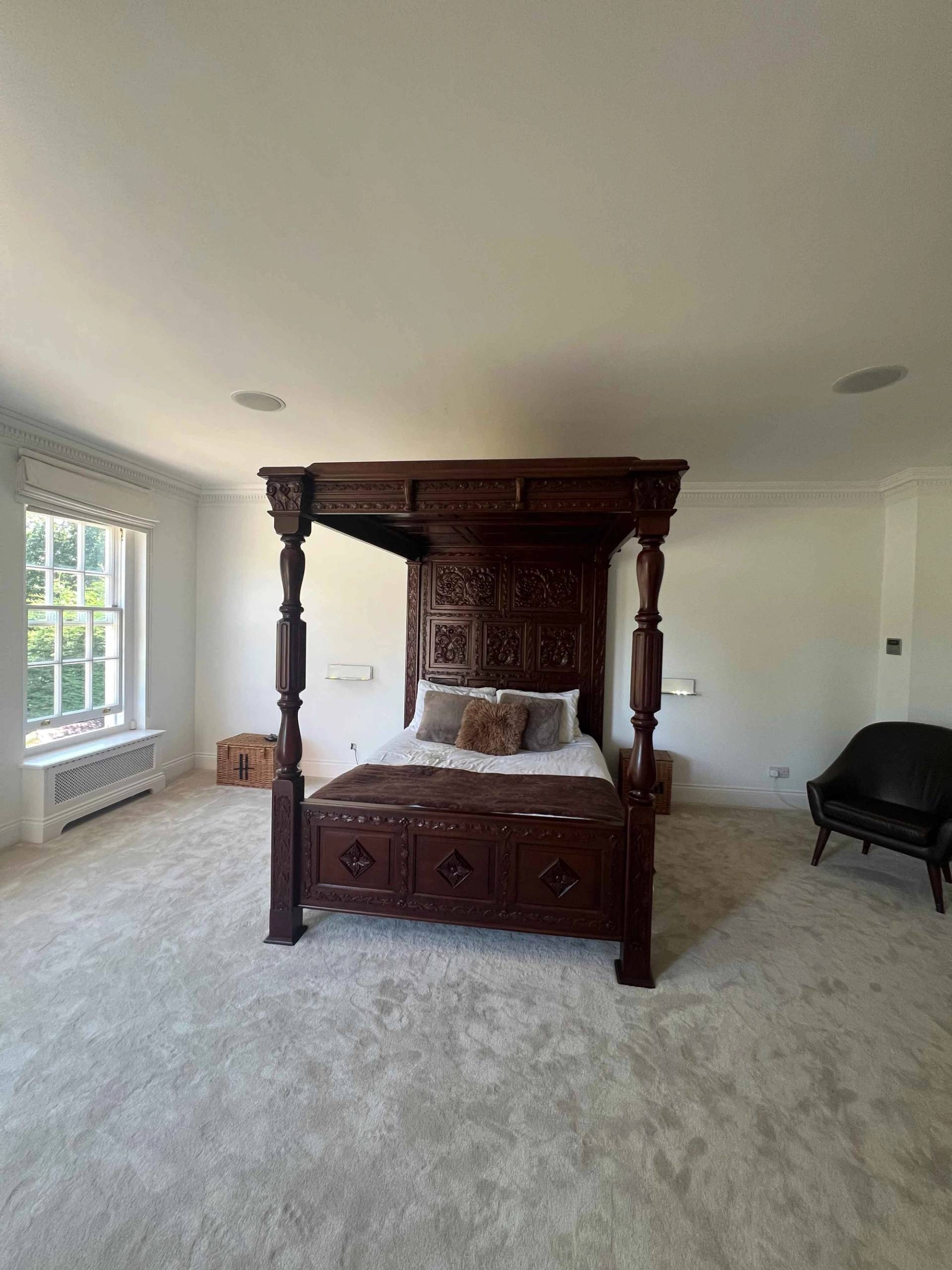 Carved four-poster bed set in a spacious master bedroom with sash windows and beige carpet, Love Locations BR7.