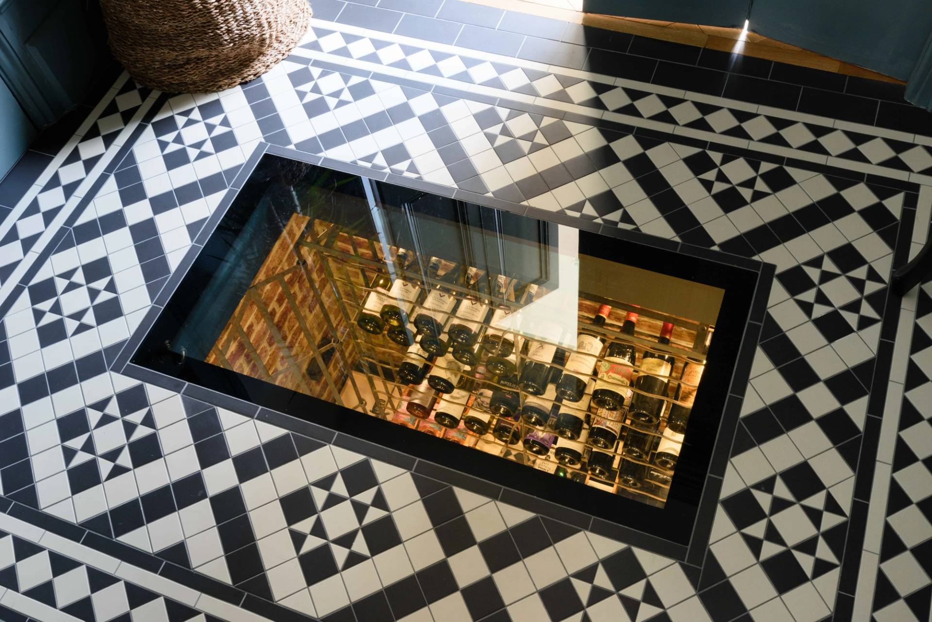 Glass floor viewing panel revealing a illuminated subterranean wine cellar set below geometric tiles, Love Locations TW11.