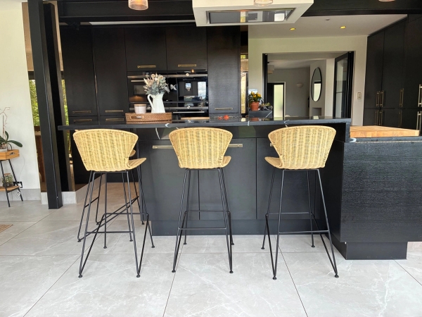 Modern kitchen breakfast bar location in Essex CM4 by Love Locations, highlighting woven counter stools set against a dark kitchen island backdrop.