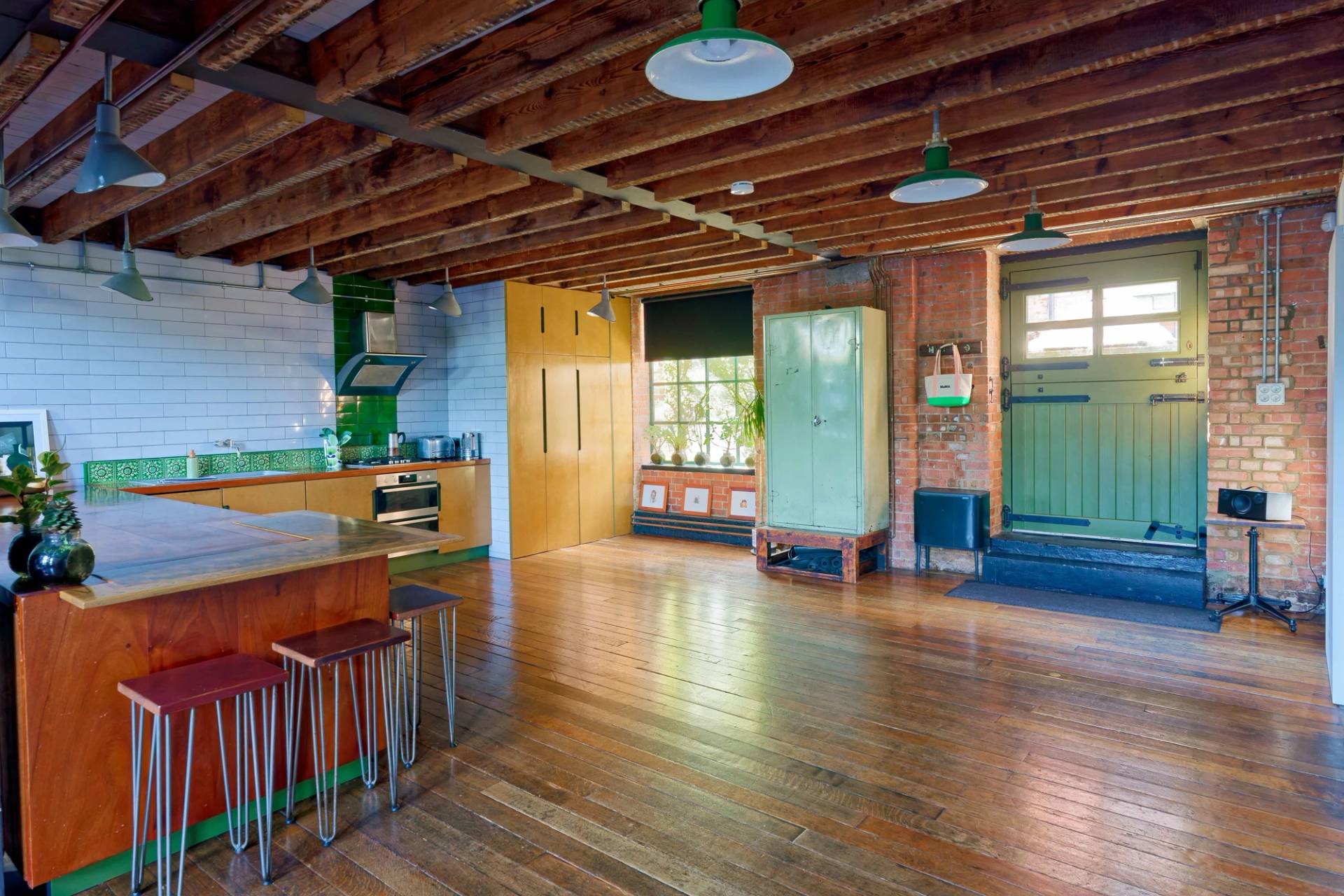 Bright open-plan warehouse kitchen with yellow cabinetry, timber island, exposed brick, and dark timber floors, Love Locations E14.