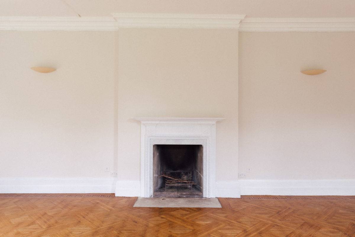 Minimalist reception room featuring a classic white marble fireplace hearth and herringbone parquet floorboards, perfect for furniture lookbooks, Love Locations SE15.