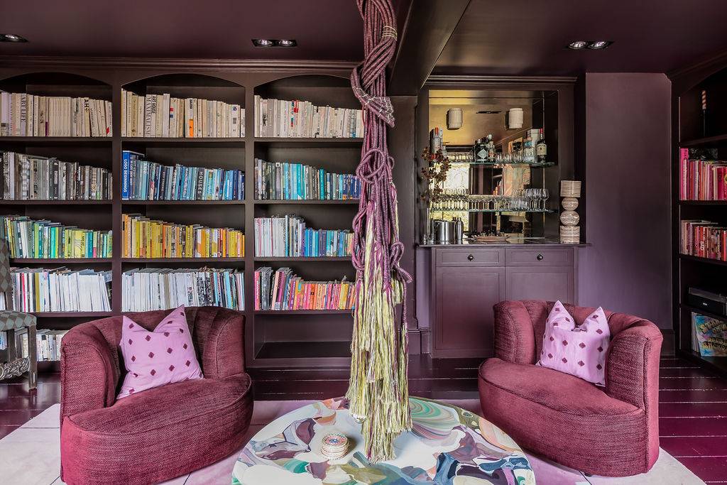 Floor-to-ceiling dark plum bookcases filled with antique books, providing a scholarly backdrop for television productions via Love Locations.