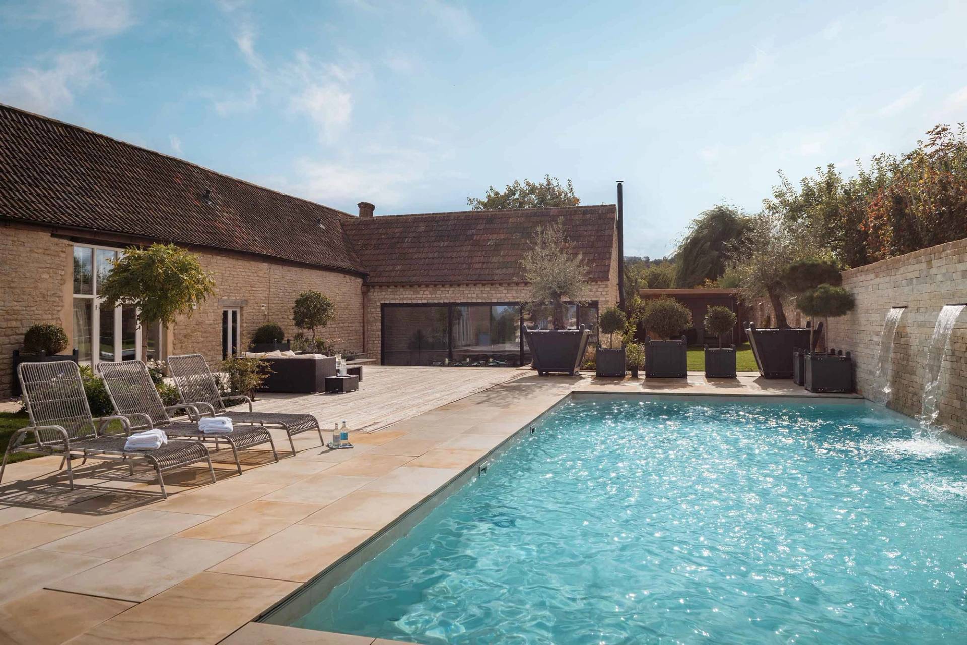 Clear blue outdoor swimming pool and stone pool house location house in Cheltenham GL51 by Love Locations.