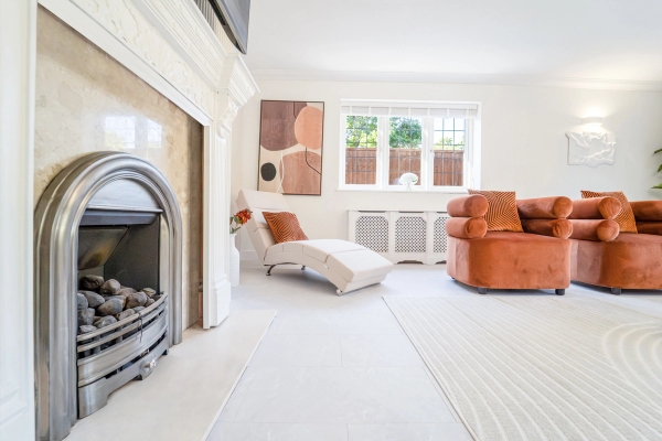Formal sitting room view showing a classic fireplace hearth, armchairs, and bay window light, Love Locations RM11.