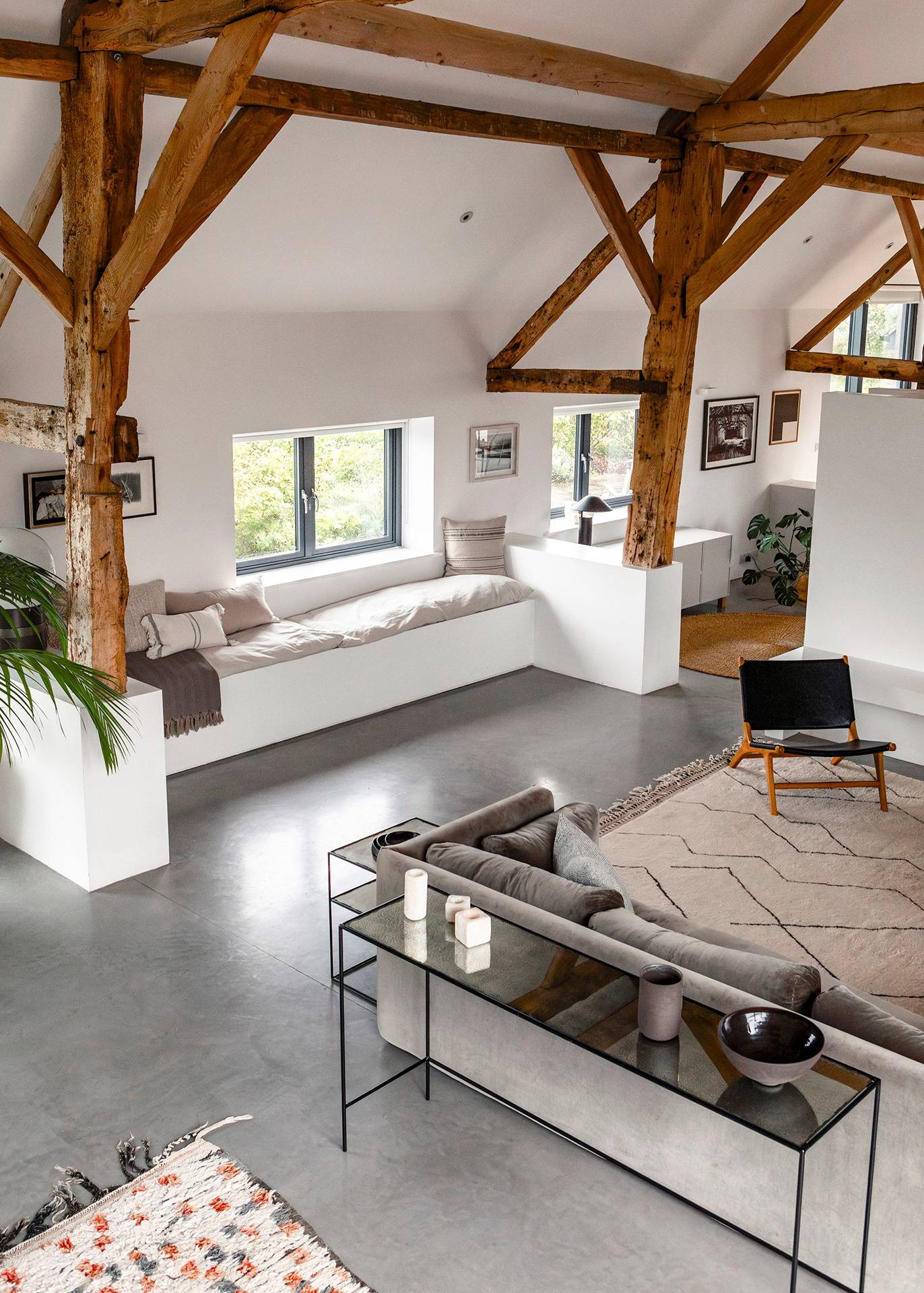 Vaulted lounge room featuring built-in window bench seating, grey corner sofa, and polished concrete floors, Love Locations SN8.