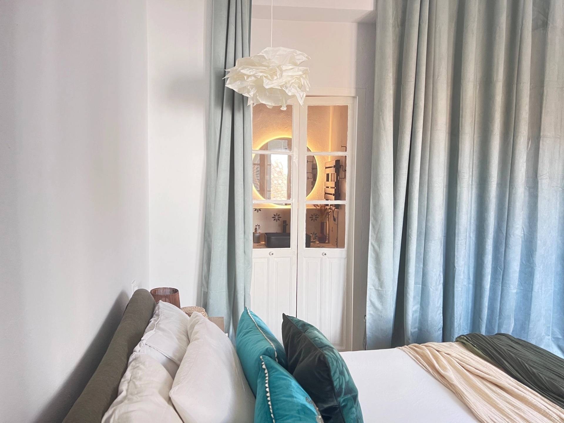 Close-up bedroom detail in Jimena de la Frontera by Love Locations, showing white wardrobe doors and sheer curtains framing soft light.