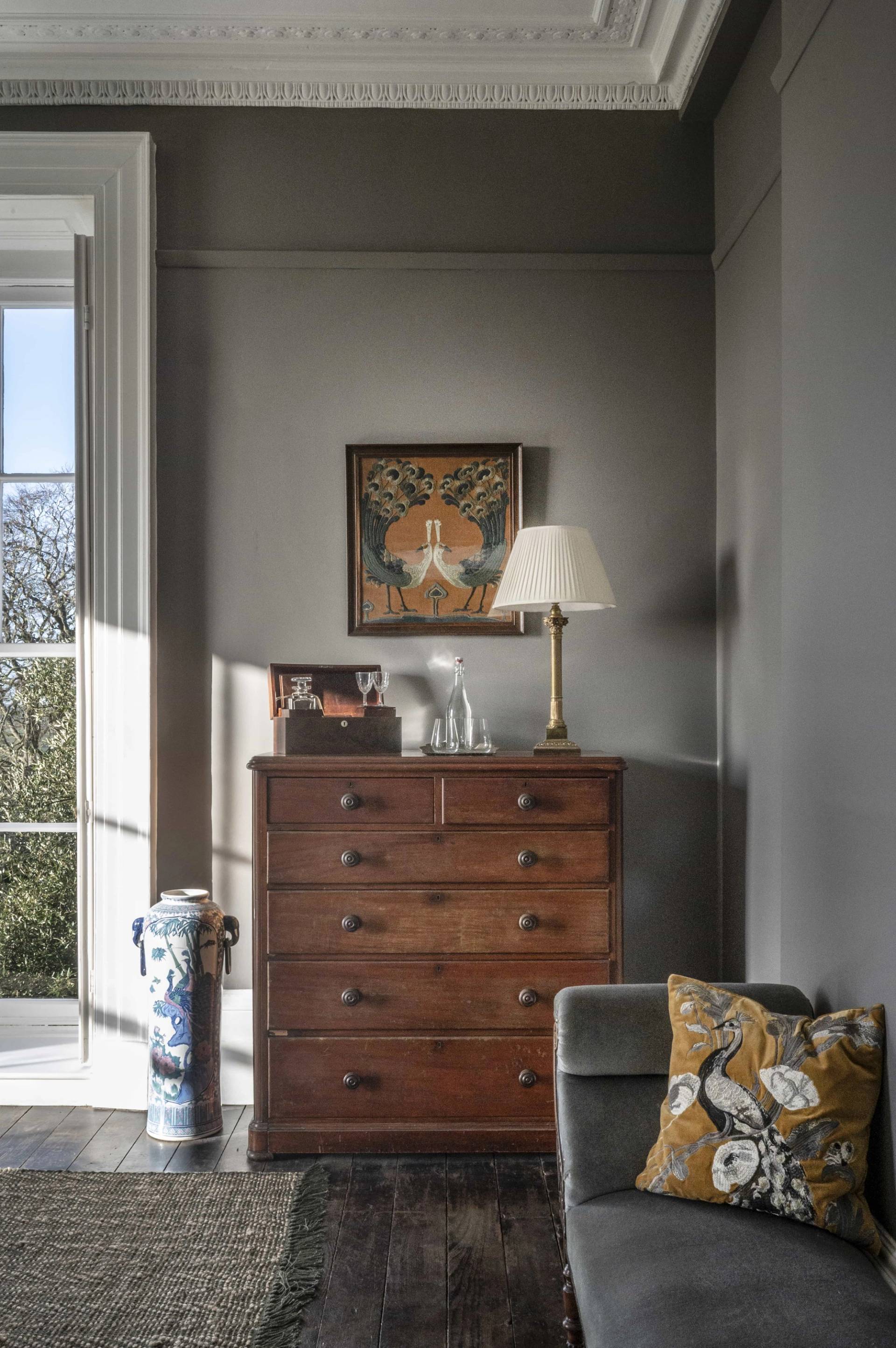Antique wooden chest of drawers set against grey plaster walls with natural sunlight streaming in, perfect for furniture advertising, Love Locations LE7.