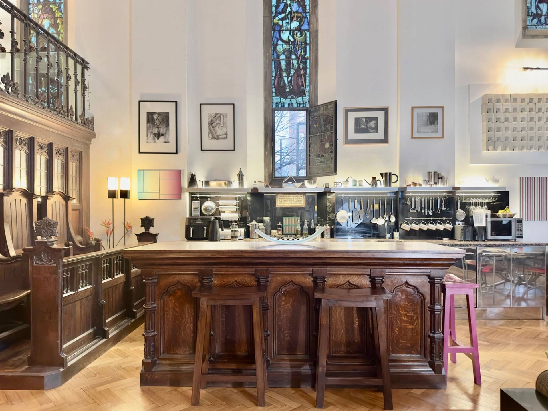 Wooden kitchen bar counter with stool seating beneath original chapel archways in an Oval SE5 film venue from Love Locations.