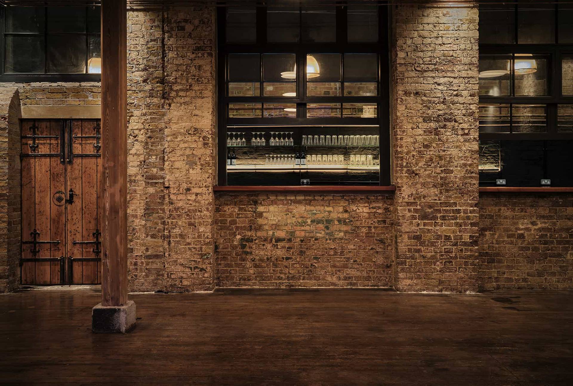 Exposed brick wall feature with a window opening into an adjoining bar area in a Shoreditch venue, Love Locations E2.