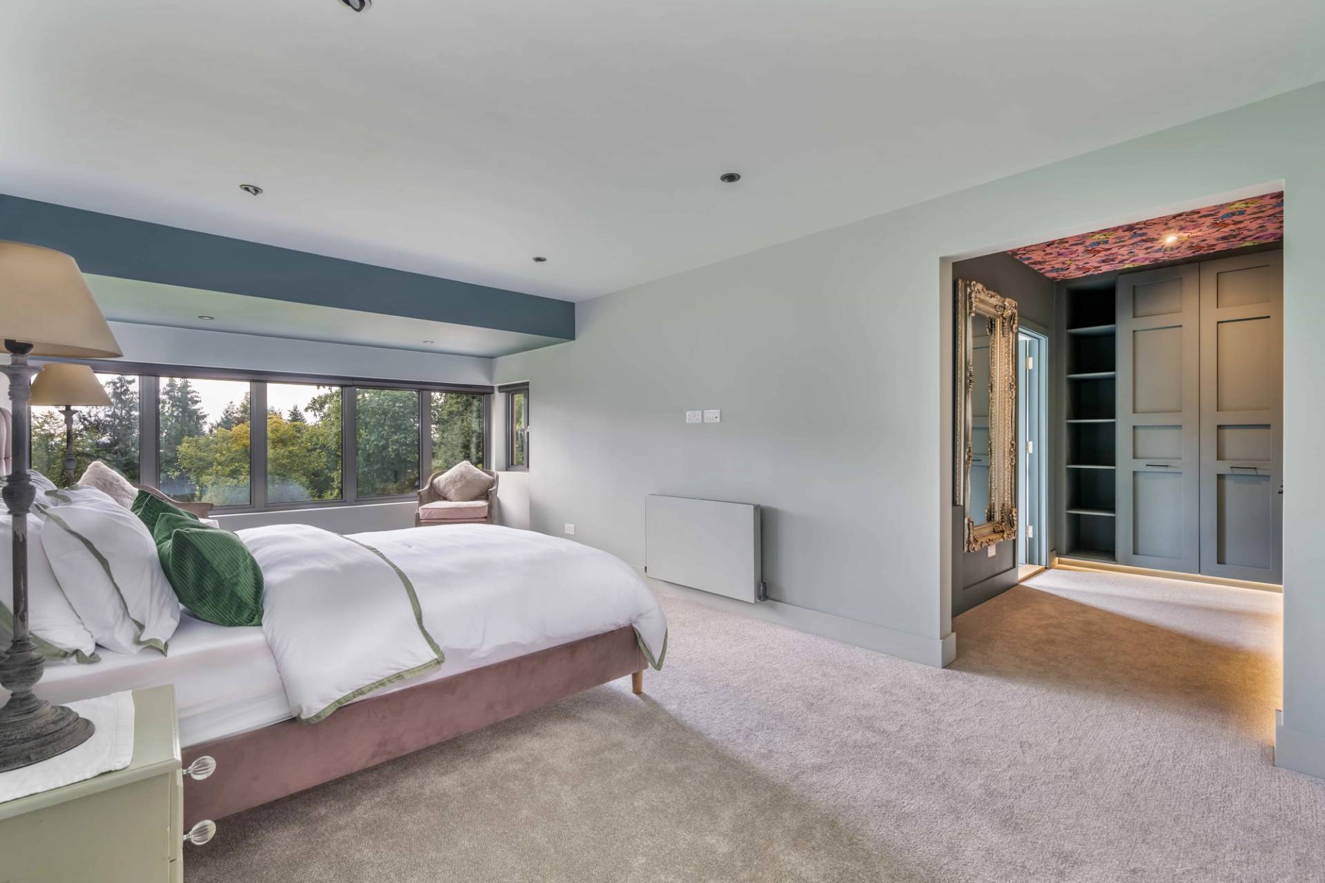 Spacious guest bedroom with dual-tone pastel walls, plush carpet, and large picture windows, Love Locations.